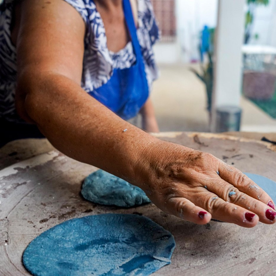 Local cook pressing blue corn tortillas on a comal beside grilling meat