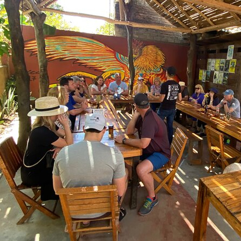 Guests enjoying a meal under a palapa with colorful murals during the tour