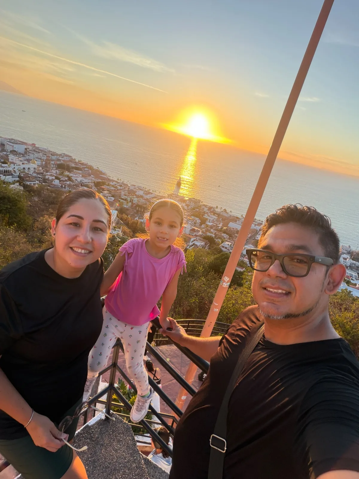 Pepe García with his wife and daughter at a Puerto Vallarta lookout at sunset over Banderas Bay
