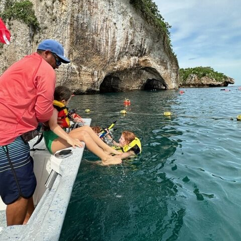Guide helping guests with snorkel gear at Los Arcos